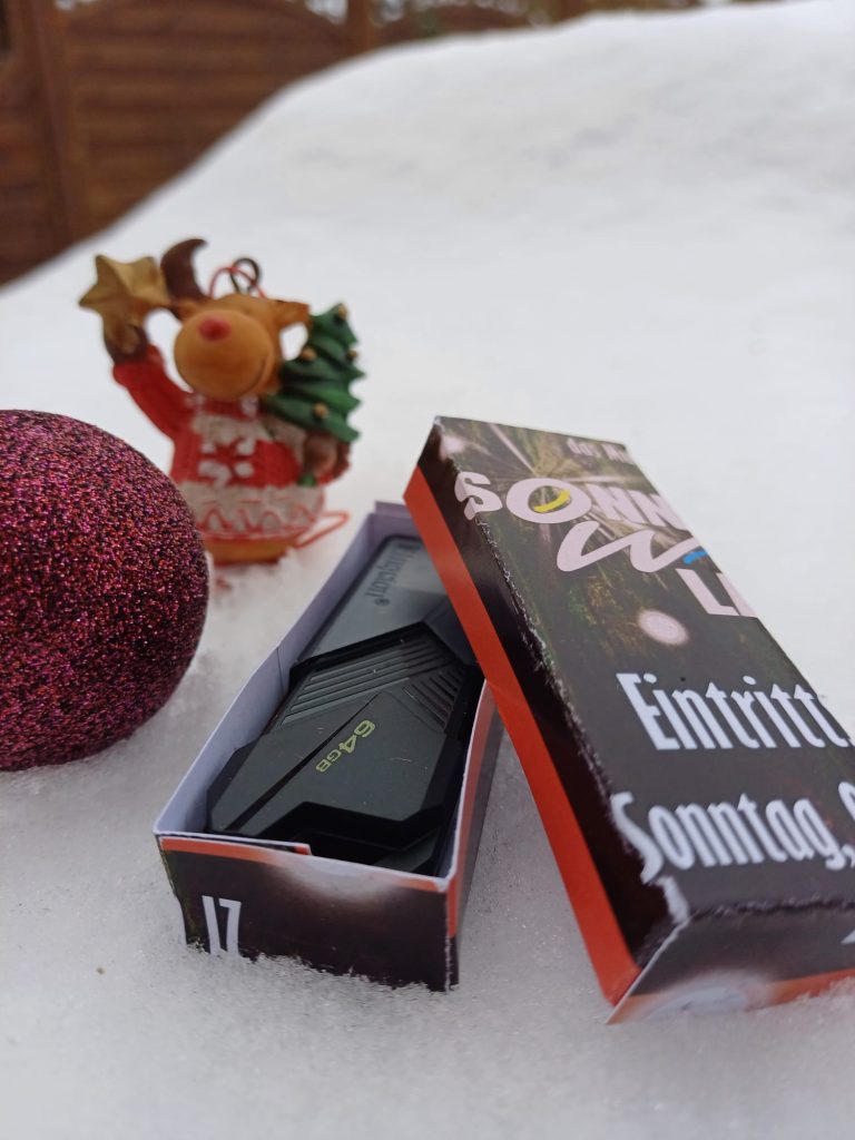 Der USB-Stick in seiner Verpackung in weihnachtlich, winterlichem Umfeld.